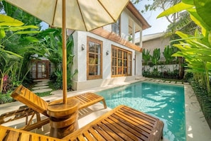 A poolside area with wooden lounge chairs and a pergola. - Brand New Oasis Villa, Large Pool, Central Ubud (Kabupaten Gianyar)