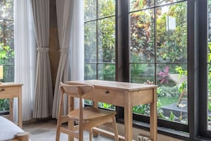 A wooden desk with a chair in a room with large windows. - Cozy Ubud's 2BR Escape with Huge Pool & Patio (Ubud)