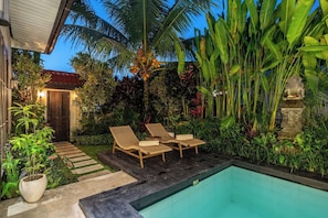A poolside area with two lounge chairs, a small pool, and lush tropical vegetation. - Cozy Ubud's 2BR Escape with Huge Pool & Patio (Ubud)