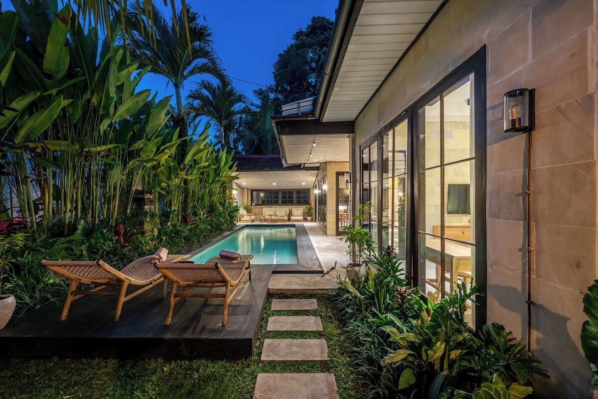 Une maison moderne dotée d’une piscine, d’un espace salon extérieur et d’une végétation luxuriante.