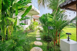 Ein üppiger Garten mit einem Weg, der zu einer Villa führt.