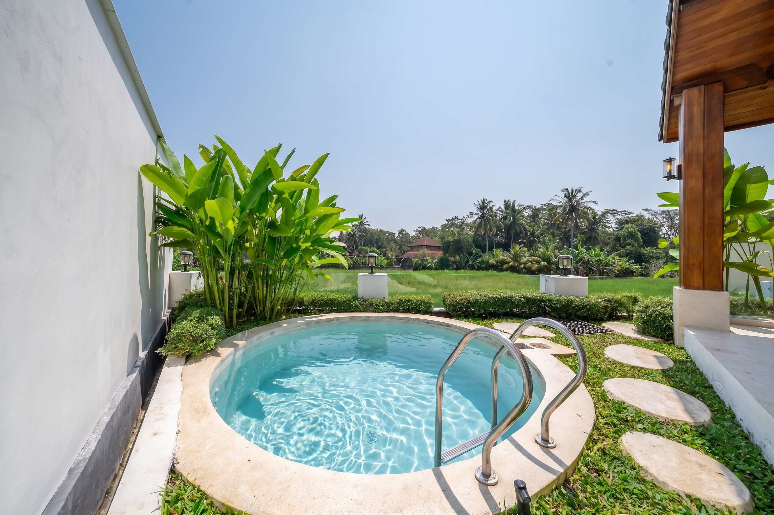 A swimming pool with a clear blue water surface, surrounded by a concrete deck and stone stepping stones.