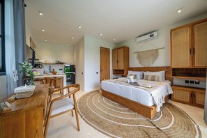 A modern bedroom with a large bed, wooden furniture, a kitchen area, and a dining table. - Tropical 1BR w Private Pool&Kitchen in Ubud (Gianyar Regency)