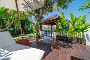 A wooden deck with a covered seating area, surrounded by lush greenery and a clear sky. - Tropical 1BR w Private Pool&Kitchen in Ubud (Gianyar Regency)