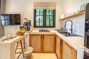 A compact kitchen with a built-in TV, a coffee maker, and a window with a view of greenery. - Tropical 1BR w Private Pool&Kitchen in Ubud (Gianyar Regency)
