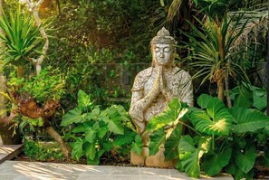 Eine Statue in einem Garten mit verschiedenen Pflanzen.