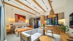 Moderni hotellihuone, jossa on sänky, sohva, ruokapöytä ja pieni keittiönurkkaus.