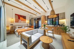 Een moderne hotelkamer met een bed, een sofa, een eettafel en een kitchenette.