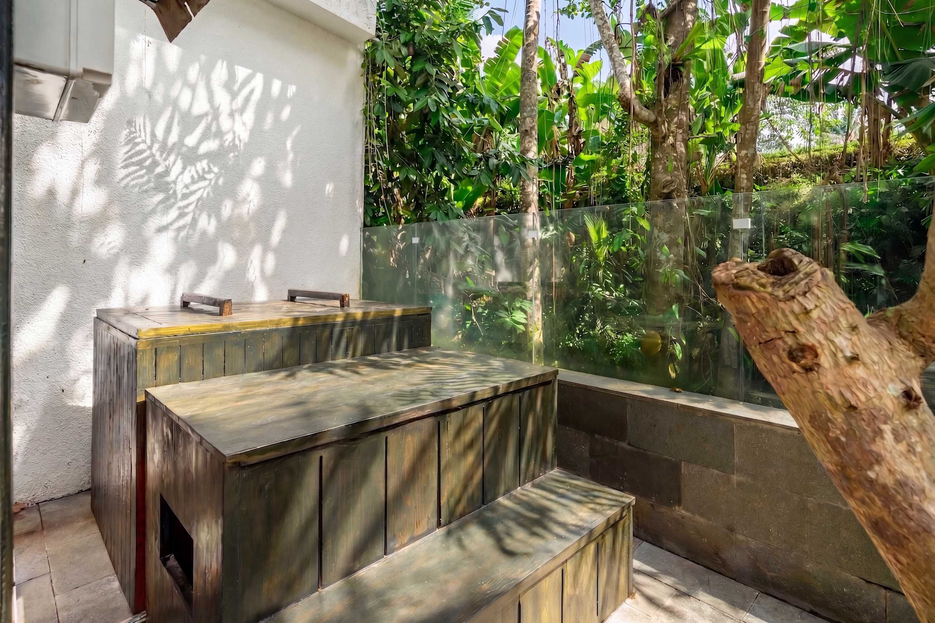 A seating area with a bench and a table, surrounded by a glass enclosure with plants.
