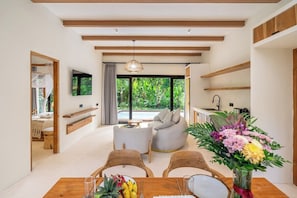 A modern interior with a dining area, seating, and a view of greenery outside. - Stylish 2BR w Garden Bath & Pool, Top Ubud's Spot (Kabupaten Gianyar)
