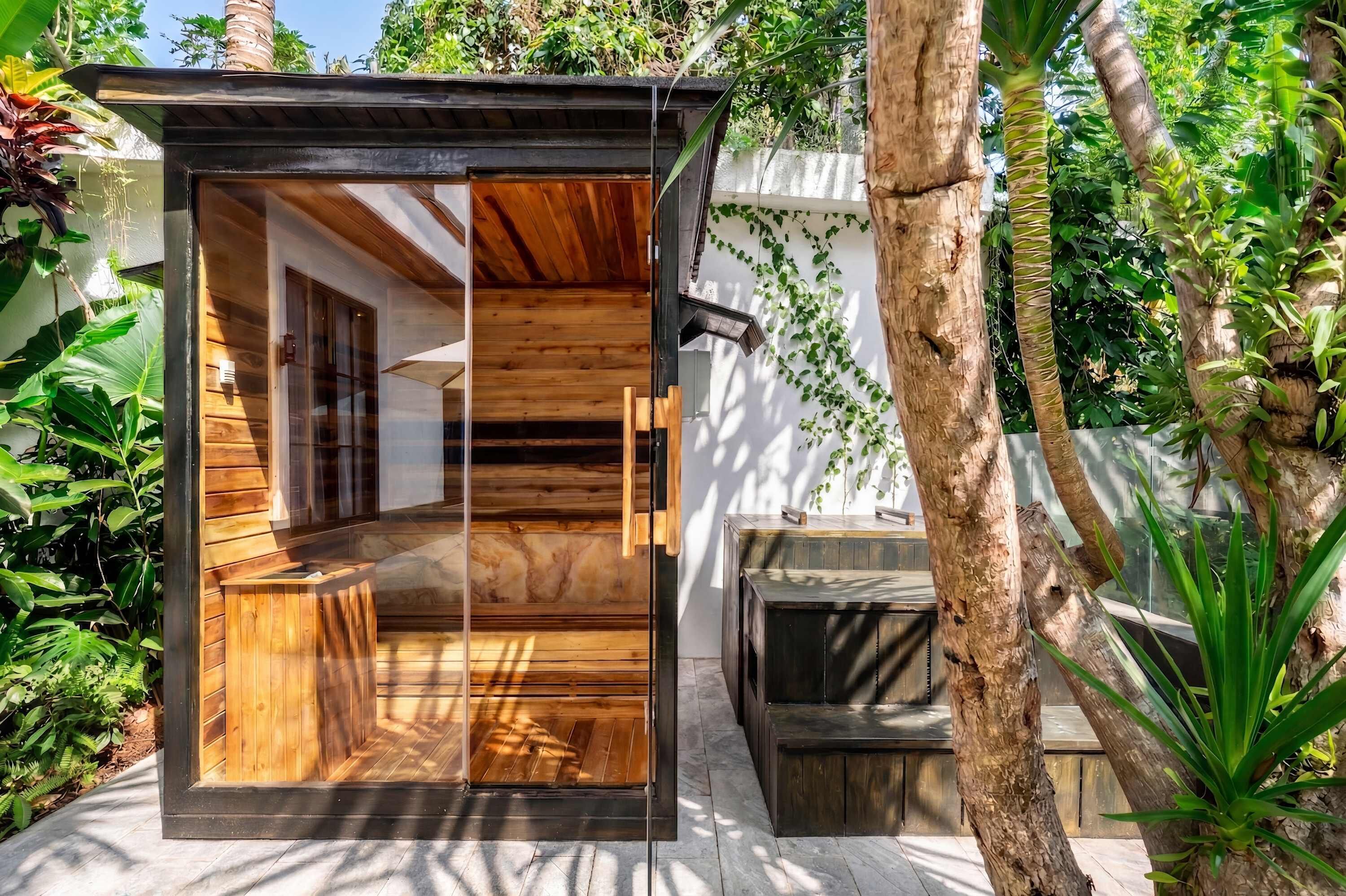 Estructura de madera moderna y cerrada con puerta de vidrio, rodeada de abundante vegetación.