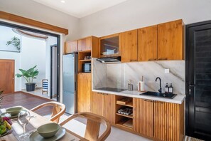 Eine moderne Küche mit Holzausstattung, einer Marmorarbeitsplatte und einem schwarzen Kühlschrank.