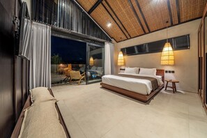 A bedroom with a large bed, a seating area, and a view through a glass door. - Badung's Best Stylish 1BR - Beaches Nearby+Pool (Badung Regency)
