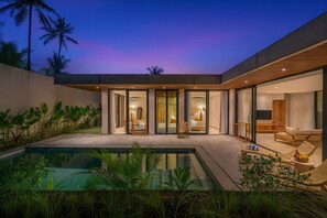 A modern house with a swimming pool, glass doors leading to a bedroom, and a lounge area with seating. - Tranquil 3BR Hideaway in Central Ubud • Huge Pool (Gianyar Regency)