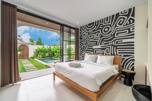 A modern bedroom with a large bed, a view of a swimming pool, and a patterned wall. - Brand NEW Villa+Amazing Jungle View+Huge Pool+4BDR (Kecamatan Kuta Utara)