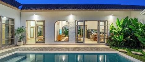 A residential property with a swimming pool, a covered patio, and a dining area.