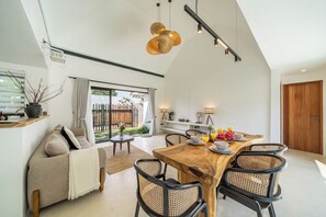Un espace repas avec une table en bois, des chaises noires et une vue sur l’extérieur.