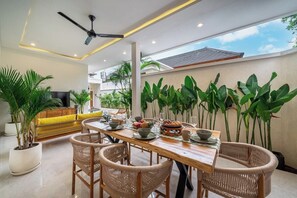 Un coin repas avec une table en bois, des chaises en osier et des plantes en pot.