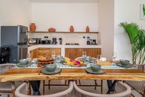 Un coin repas avec une table en bois dressée pour quatre personnes, entourée de chaises en osier.