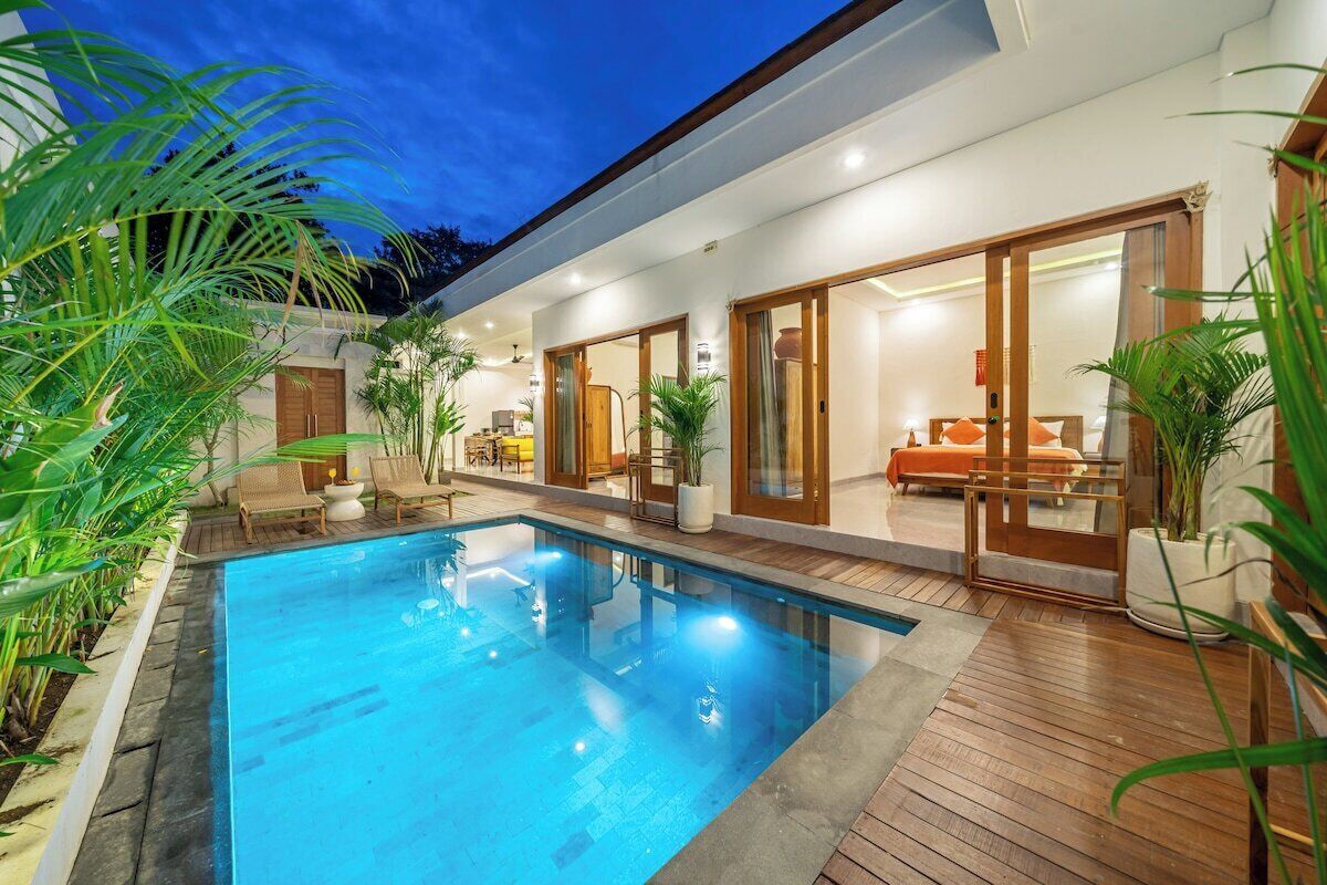 Ein modernes Haus mit Swimmingpool, Holzterrasse und Essbereich mit Gartenmöbeln.