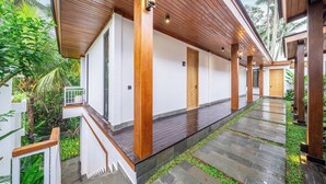 A covered outdoor area with a wooden ceiling, a stone pathway, and a white building with a door. - Cozy 1BR • Pool&Garden View • Patio • Central Ubud (Kabupaten Gianyar)