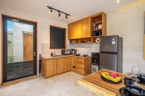 A modern kitchen with wooden cabinets, a built-in oven, and a dining area with a table set for two. - Paradise 2BR Villa w Beach Access & Private Pool (Kecamatan Kuta Utara)