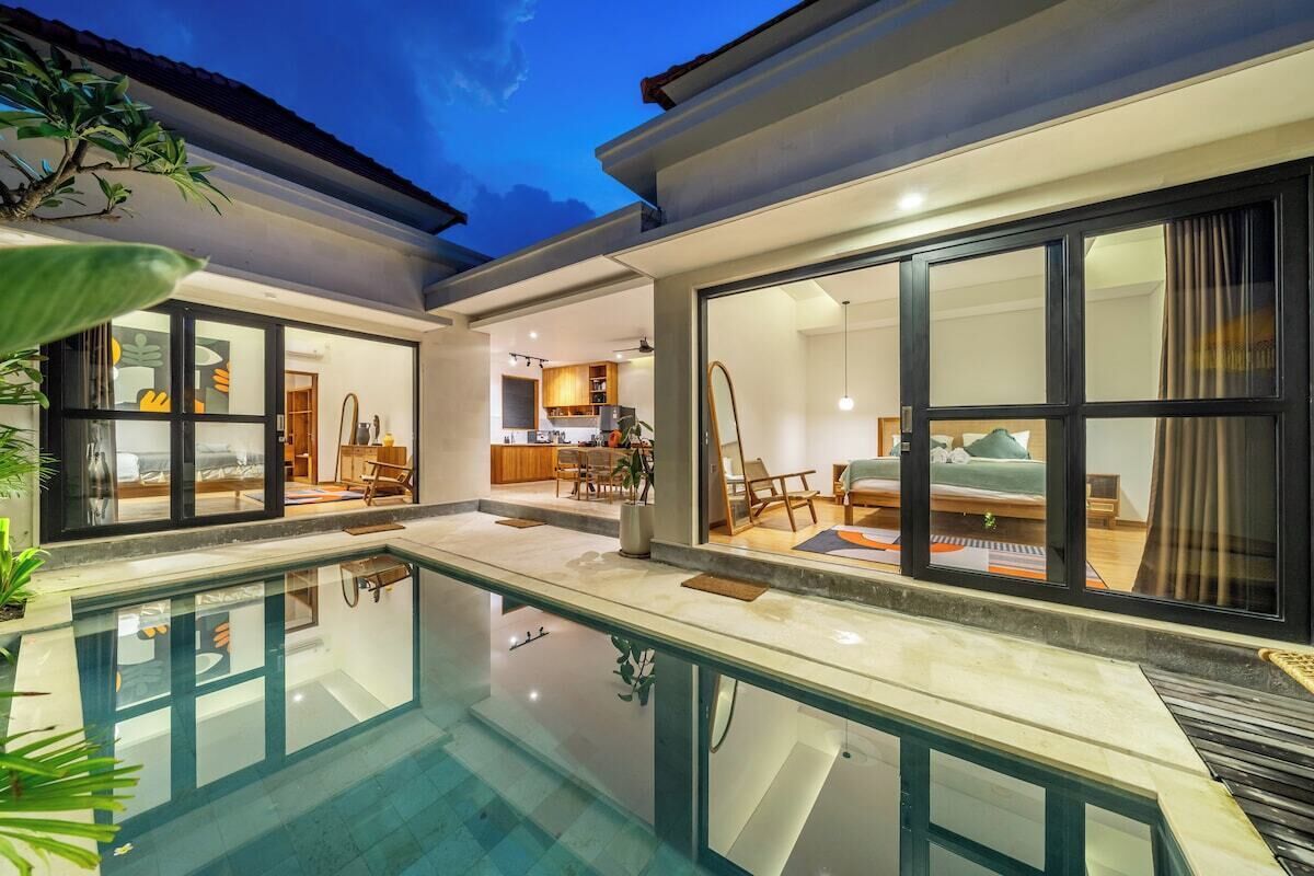 A modern house with a swimming pool, large windows, and a kitchen area.