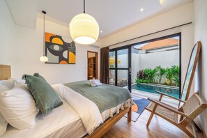 A bedroom with a bed, a chair, a large window, and a view of a swimming pool. - Paradise 2BR Villa w Beach Access & Private Pool (Kecamatan Kuta Utara)