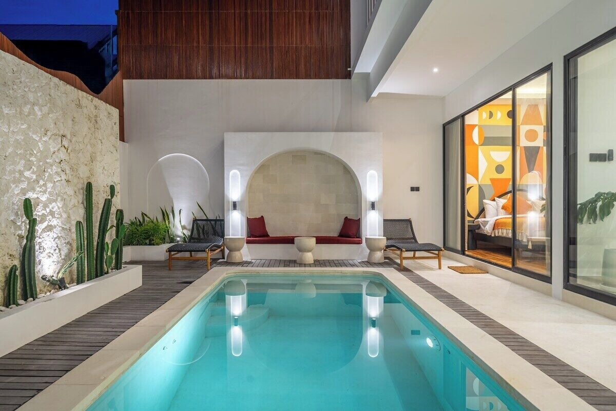 Ein Hallenbad mit Sitzgelegenheit, Holzterrasse und modernem Interieur.