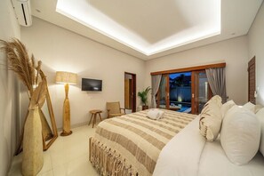 Een slaapkamer met een bed, een televisie, een stoel, een lamp en uitzicht op een zwembad.