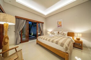 A bedroom with a bed, a chair, a nightstand, a lamp, and a window with curtains. - Brand NEW Paradise Villa, Huge Pool, Canggu (Kabupaten Badung)