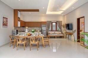 A modern living room with a dining area, a sofa set, a TV, and a kitchen in the background. - Brand NEW Paradise Villa, Huge Pool, Canggu (Kabupaten Badung)