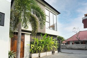 A modern building with large windows, a wooden door, and a well-maintained garden with various plants. - Brand NEW Villa+Amazing Jungle View+Huge Pool+4BDR (Kabupaten Badung)