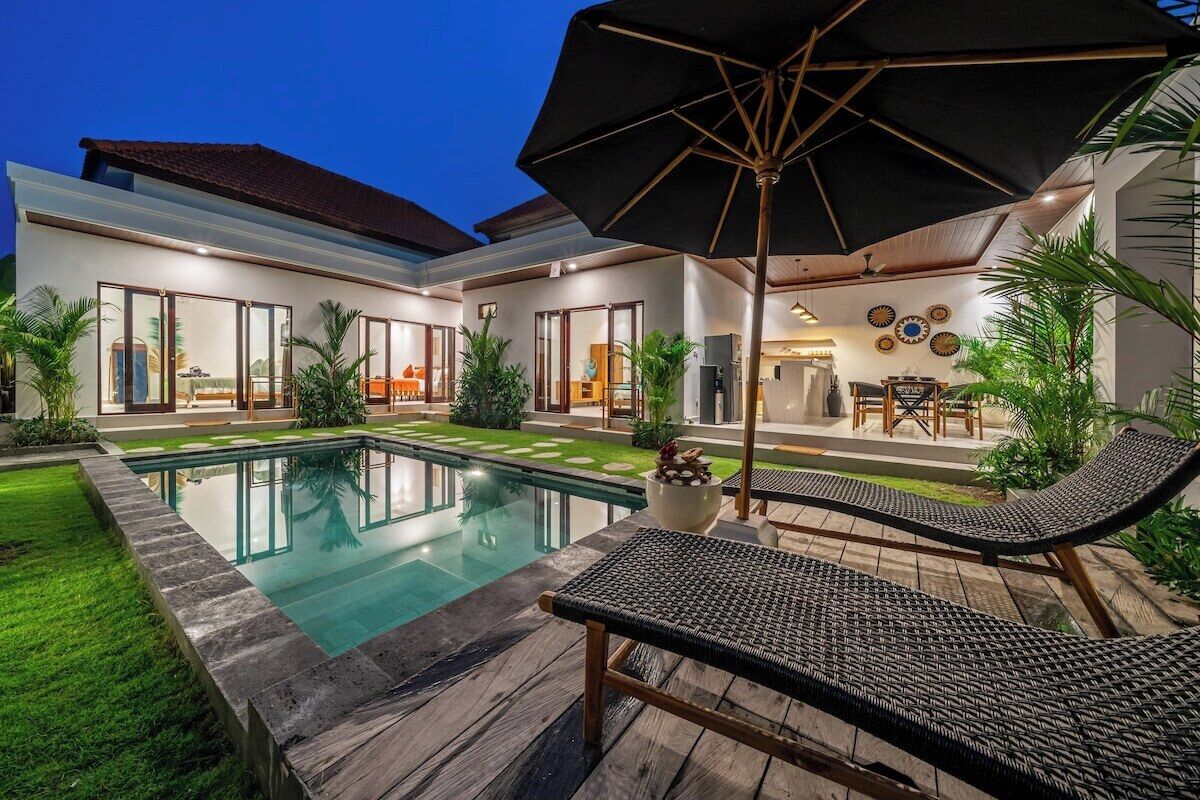 A modern outdoor pool area with lounge chairs and a large umbrella.