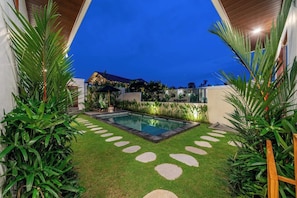 A swimming pool with a stone pathway leading to it, surrounded by lush greenery and a well-maintained lawn. - Brand NEW Villa+Rice Fields View+Huge Pool+4BDR (Kecamatan Kuta Utara)