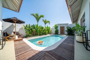 A rooftop swimming pool with a wooden deck, surrounded by tropical plants and a lounge area with chairs and an umbrella. - Brand New Paradise 2BDR Villa, Large Pool, Canggu (Kabupaten Badung)