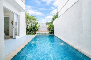 A swimming pool with a clear blue water surface, surrounded by a white wall and a wooden deck. - Chic 3BR in Nusa Dua - Ocean View, Cinema, Rooftop (Kabupaten Badung)