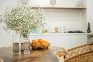A wooden table with a vase of white flowers, a bowl of oranges, and two clear glasses. - Chic 3BR in Nusa Dua - Ocean View, Cinema, Rooftop (Kabupaten Badung)
