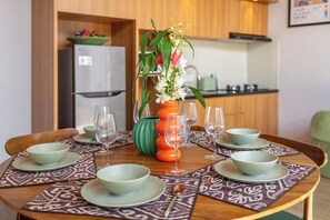 Ein Esstisch, gedeckt mit Schalen und Weingläsern, eine Vase mit Blumen und eine grüne dekorative Schale.