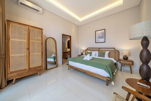 Ein Hotelzimmer mit Bett, Kleiderschrank, Spiegel, Nachttisch und Lampe.