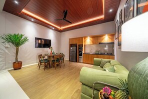 Ein modernes Wohnzimmer mit Essbereich, Küche und Deckenventilator.