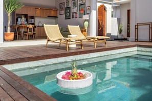 A pool area with a floating fruit basket, wicker lounge chairs, and a dining area with a table and chairs. - Brand NEW Paradise Villa, Huge Pool, Best Location (Kabupaten Badung)
