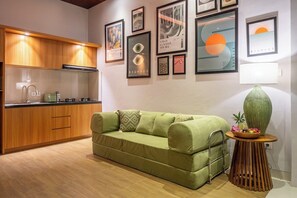 Una cuina moderna amb armaris de fusta i un sofà verd en una zona d'estar.