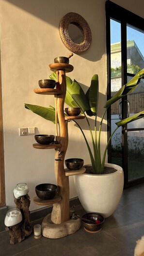 Habitació amb un mirall rodó fixat a la paret, una planta en test i una estructura de fusta que conté diversos bols.