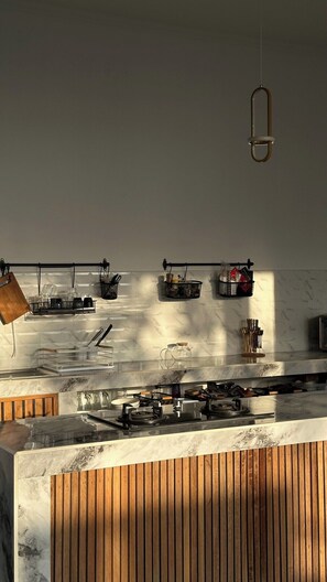 A kitchen with a marble countertop, hanging kitchen tools, and a pendant light. - Brand New 3 BDR Villa+Ricefield Views+Beach Access (Mengwi)
