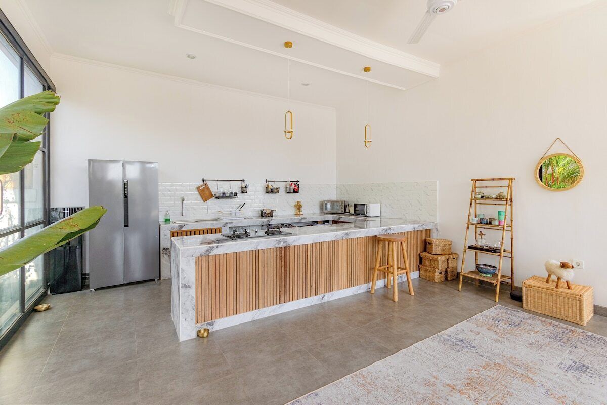 A modern kitchen with a central island, stainless steel appliances, and a wooden bar stool.