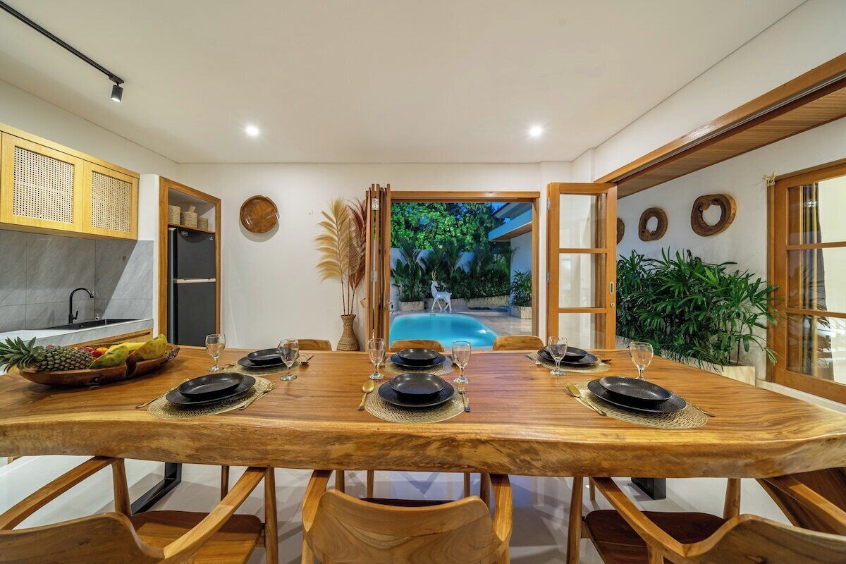 Un comedor con una mesa de madera dispuesta para seis personas, rodeada de sillas de madera.