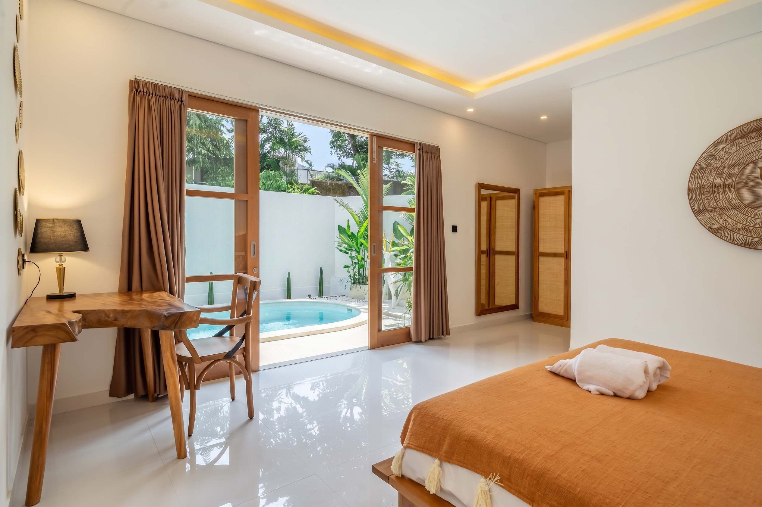 Ein Hotelzimmer mit Bett, Schreibtisch, Stuhl, einem kleinen Pool und großen Fenstern.