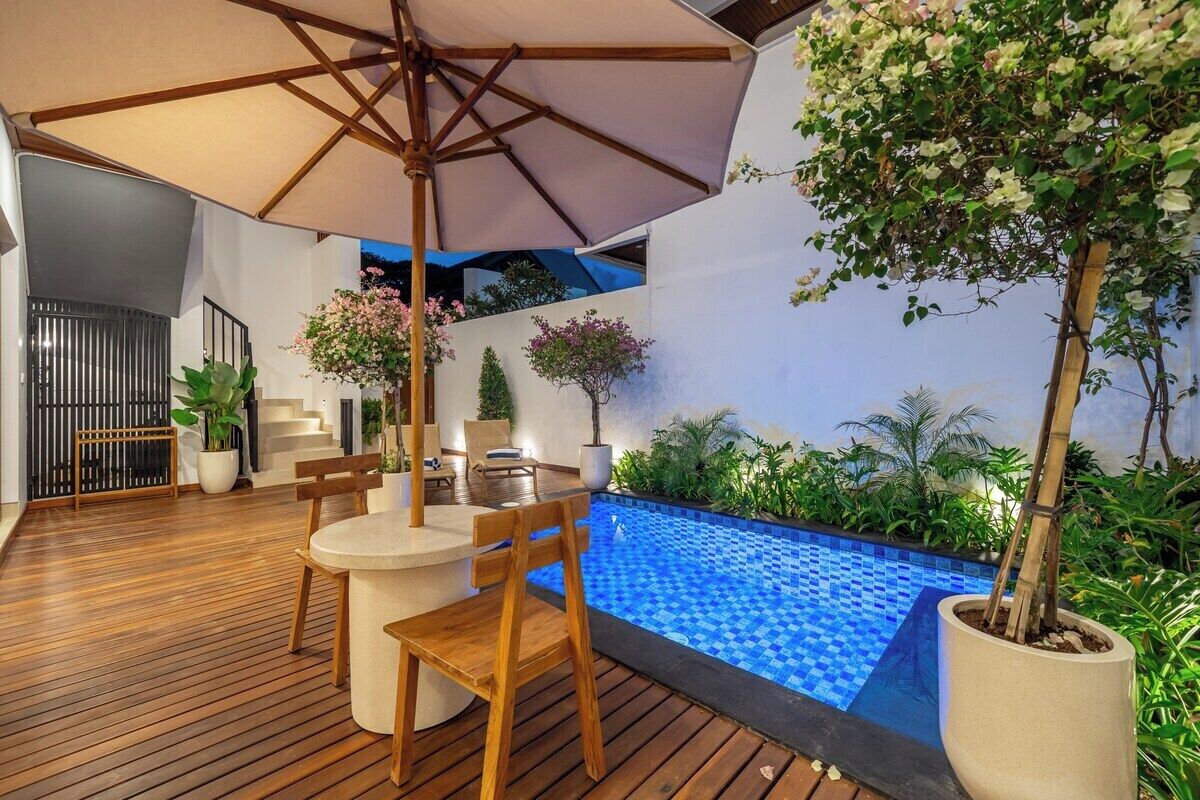 A wooden deck with a pool, outdoor seating, and potted plants.