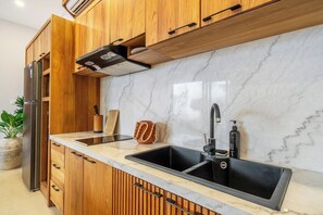 Cuina amb armaris de fusta, salabanc de marbre, vàter d'acer inoxidable i forn encastrat.